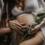 Terhes nő fehérneműben, partner öleli a hasát - szex terhesség alatt